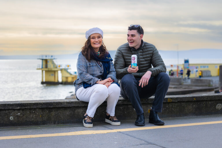 Irish artist, Cathy Hughes, and Galway Hooker's managing director sitting on Salthill Promenade. 